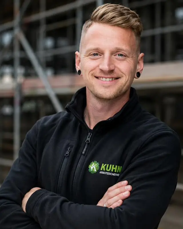 Janis Kuhn in Arbeitskleidung vor einem Industriebetrieb in der Oberlausitz