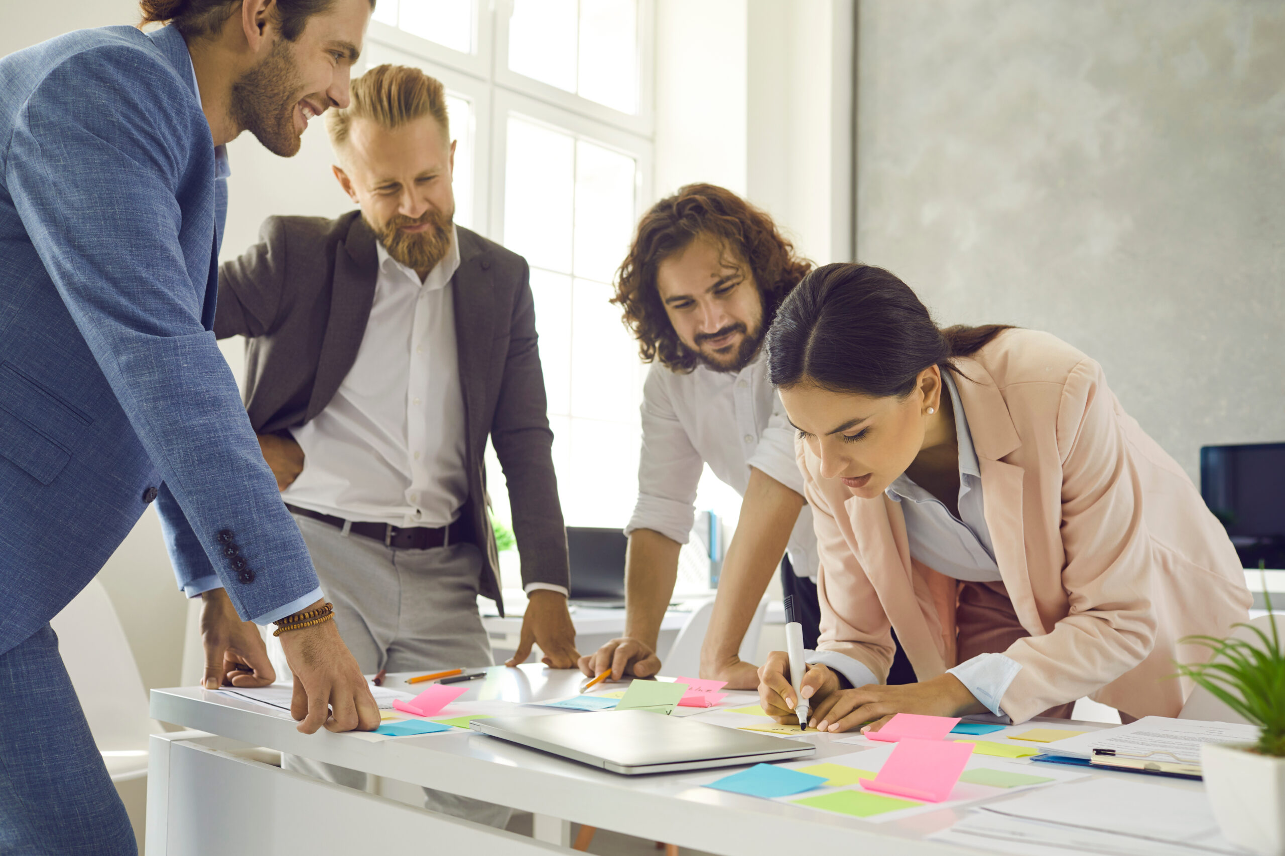 Diverse employees engaged in creative thinking in office Smiling diverse employees engaged in creative thinking at casual meeting in office. Happy multiracial businesspeople work with pads brainstorm develop business strategy. Plan, teamwork concept.