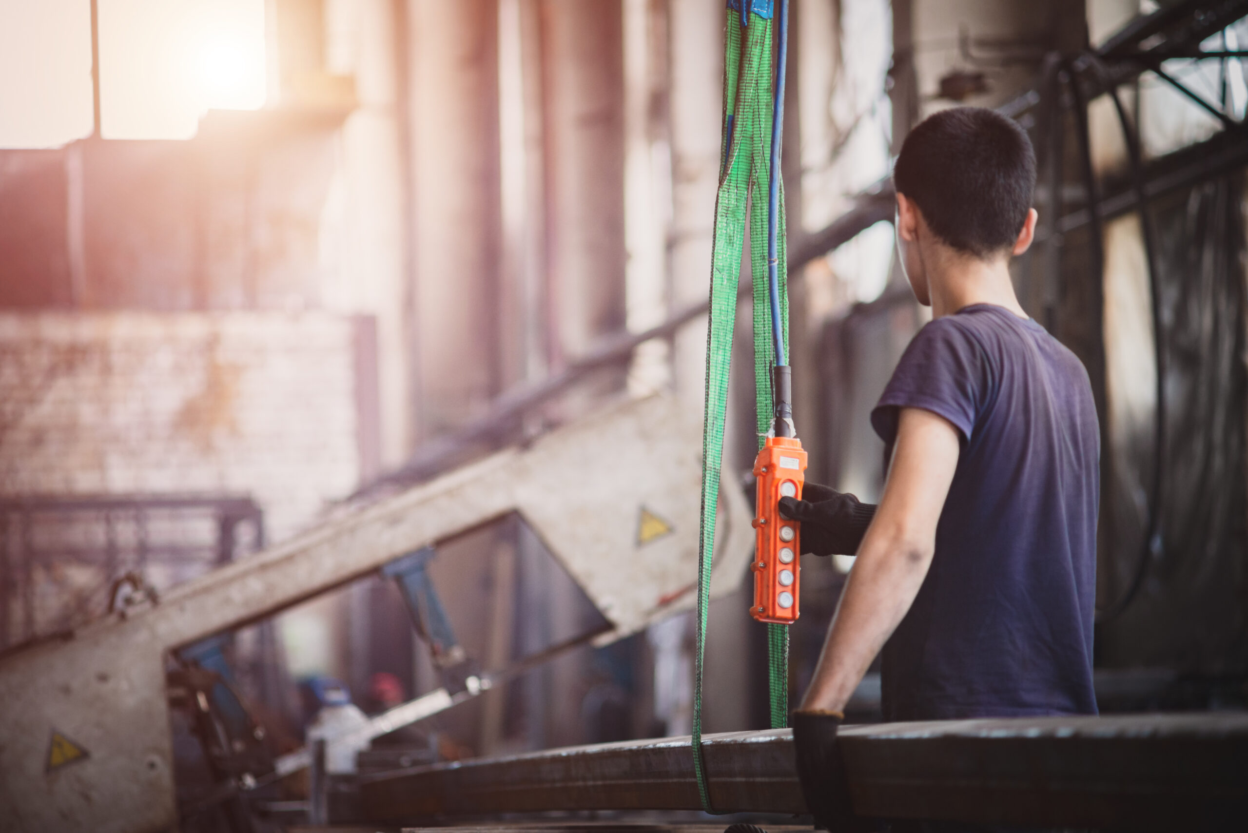 Worker with a crane lifts a long metal profile